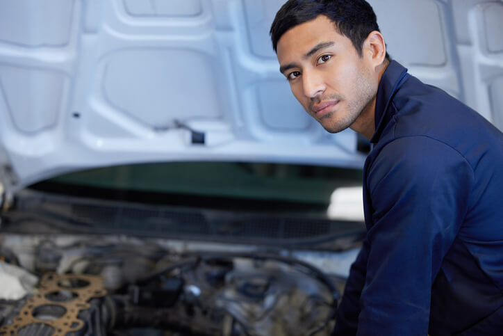 Male auto mechanic working on an EV after completing her automotive training