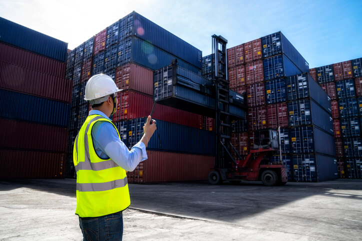 A male load planner controlling the loading of container boxes in a warehouse after completing his dispatch training