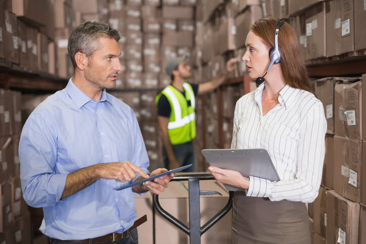 A male load planner interacting with a female colleague at a warehouse after completing his dispatch training