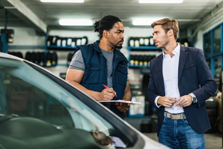 A friendly male hybrid and electric vehicle mechanic interacting with customers