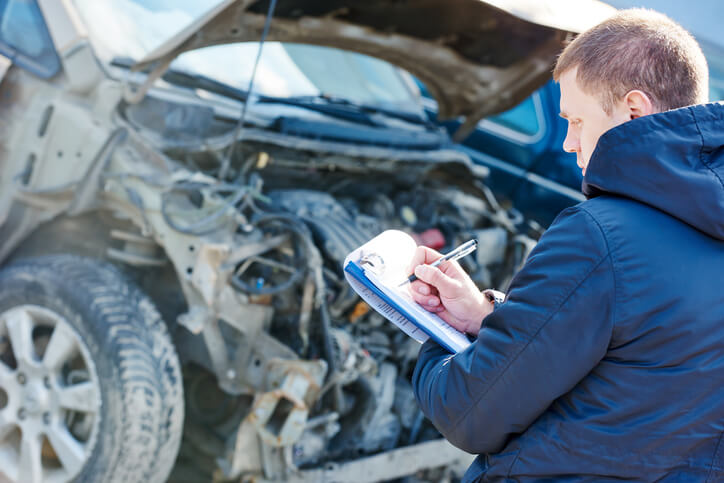 A male collisions estimator inspecting a damaged vehicle after his auto body estimating training