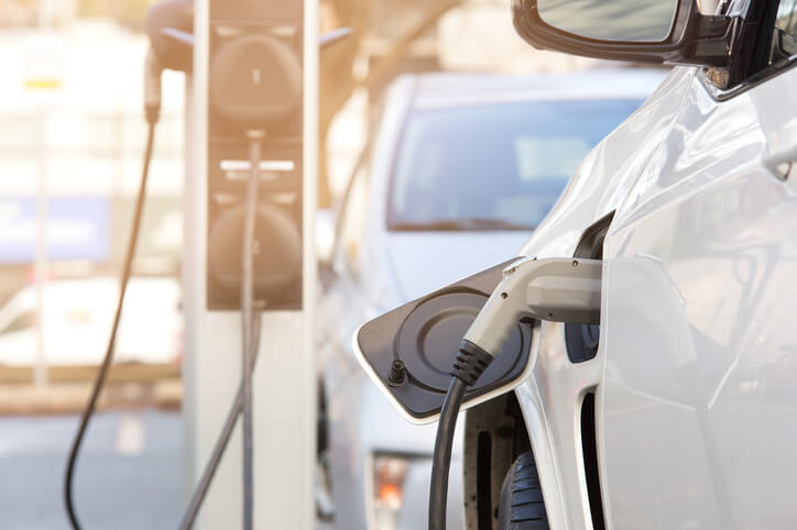 An auto mechanic plugging in a hybrid car