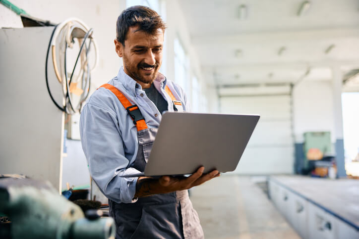 auto mechanic program grad using a laptop in a garage