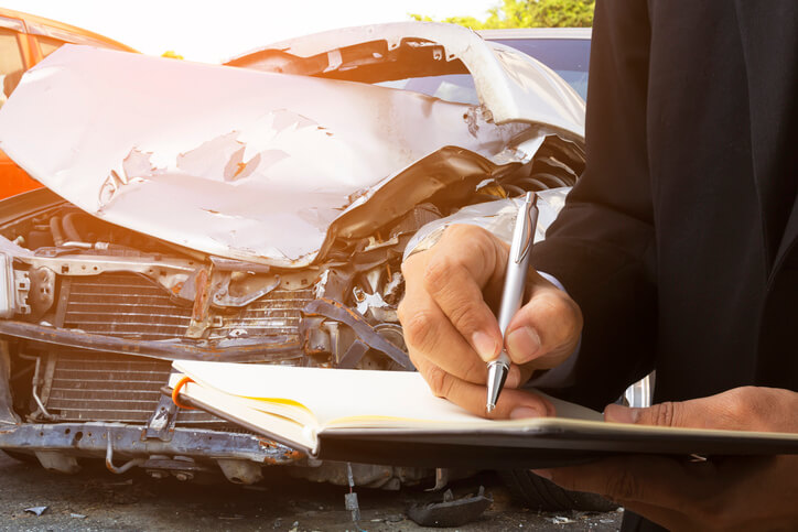 An auto mechanic inspecting a wrecked car after completing his auto body training