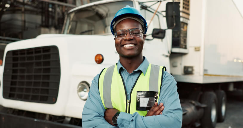 A smiling dispatch training grad smiling in front of a truck