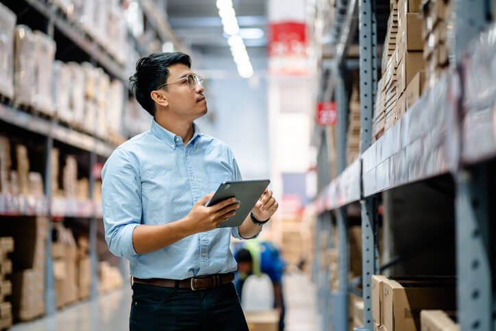 A male warehouse supervisor using a digital tablet to check the stock inventory after completing dispatch training