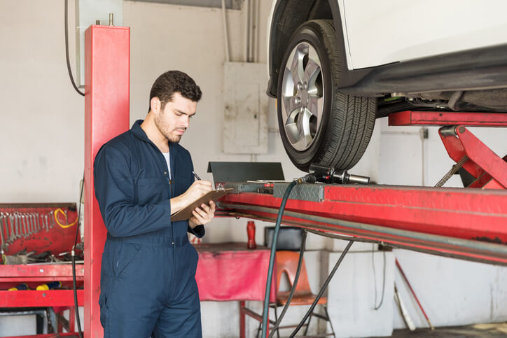 An auto body estimating training grad inspecting a car wheel