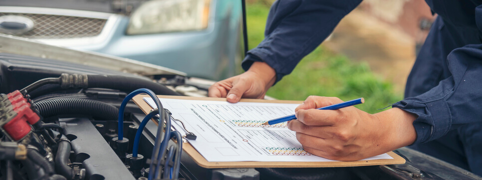 A male auto mechanic inspecting the engine of a car after his collision estimating training