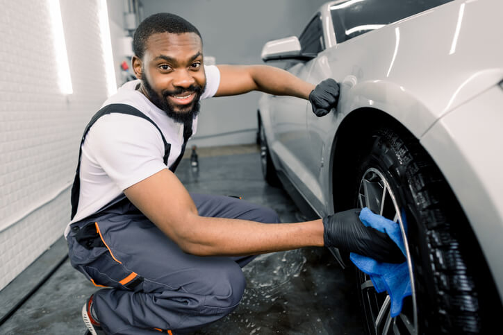 A male auto detailing professional washing the body of a car after completing his auto detailing training