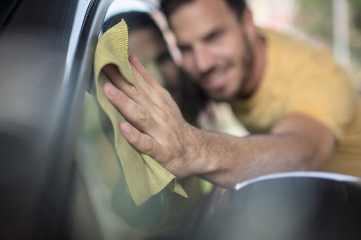 An auto detailing training grad wiping a waxed car