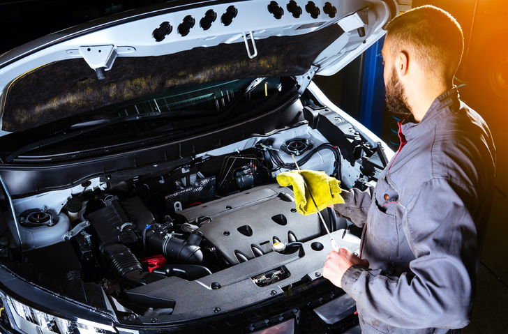 Auto mechanic checking the oil level after completing his auto mechanic training