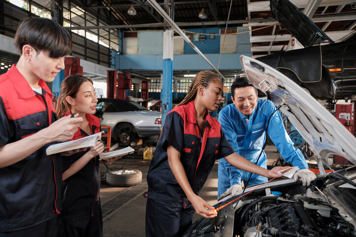 An auto mechanic training students watching an instructor do a demonstration