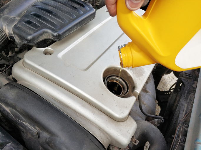 Auto mechanic changing a car’s engine oil after completing his auto mechanic training