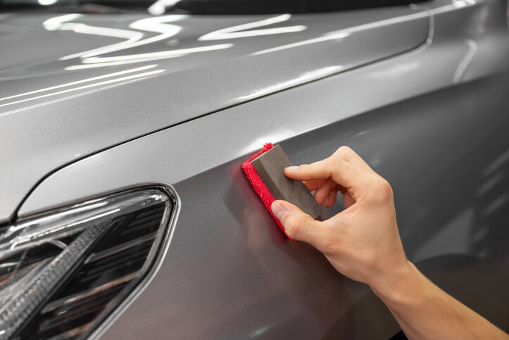 An auto detailing training grad wax a grey car