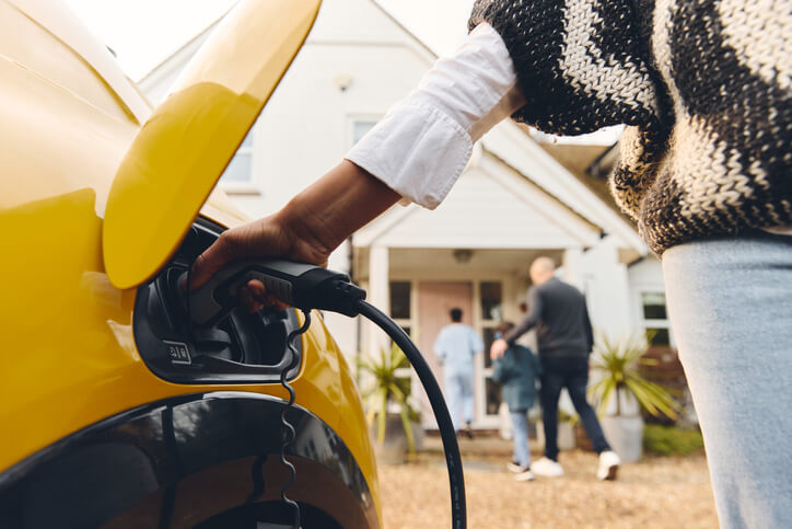 An automotive training graduate plugging in their hybrid car