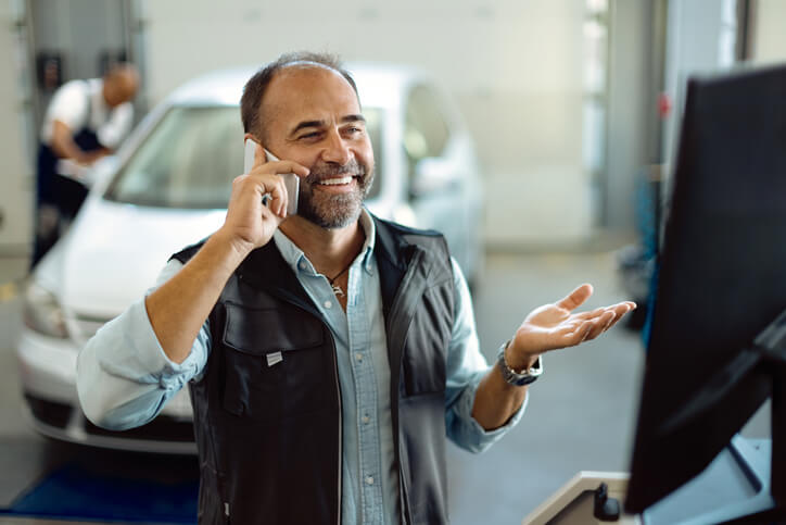 An auto body training grad speaking on a smartphone