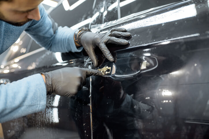 A male auto detailer gently polishing the exterior of an electric vehicle after completing his auto detailing training