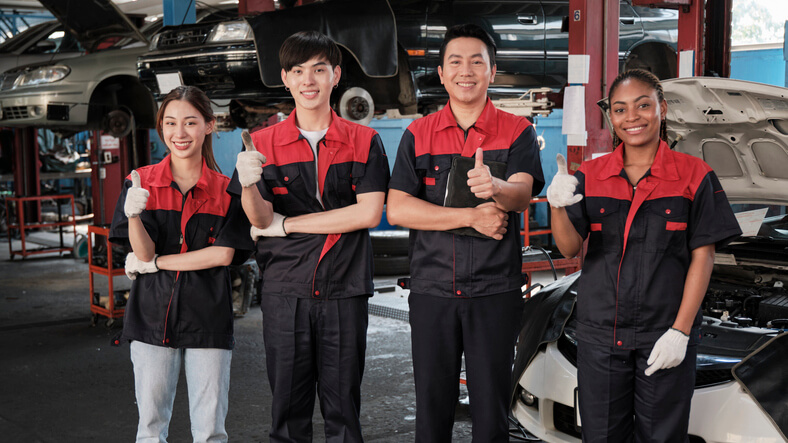 A group of students in auto mechanic school posing with their instructor