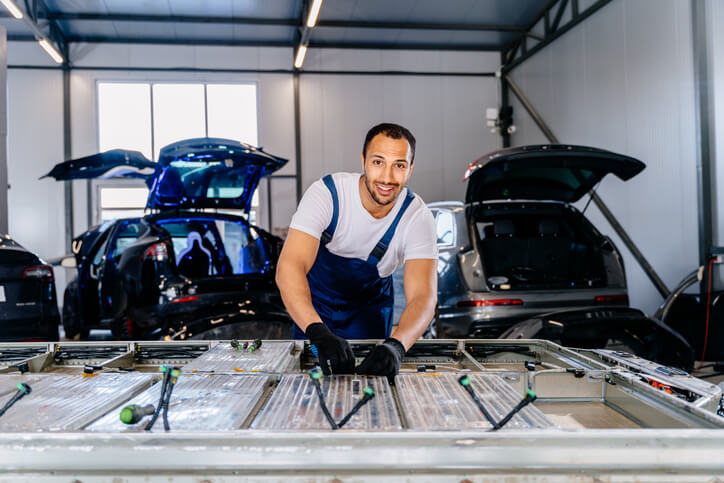 An automotive school graduate repairing electric vehicle batteries