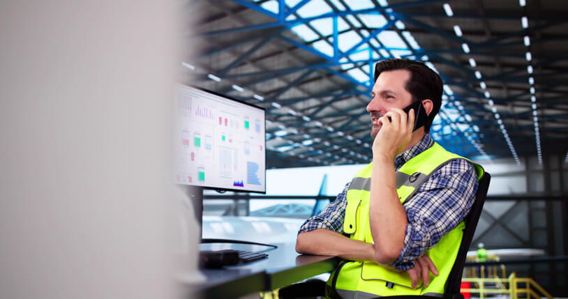 A male transportation coordinator on the phone with a driver after completing his dispatch training