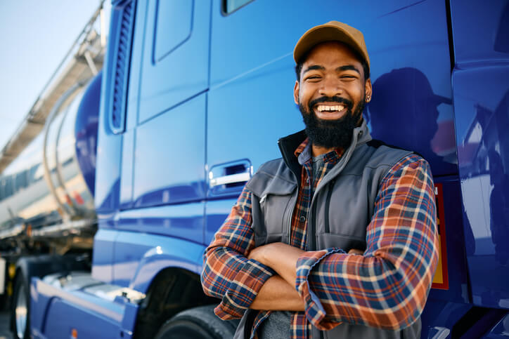 A smiling dispatch training grad posing in front of a truck