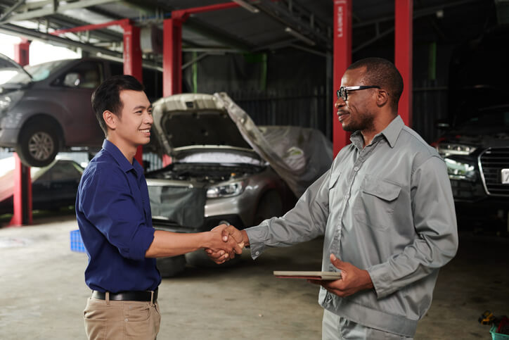 An auto mechanic school grad shaking hands with a garage manager