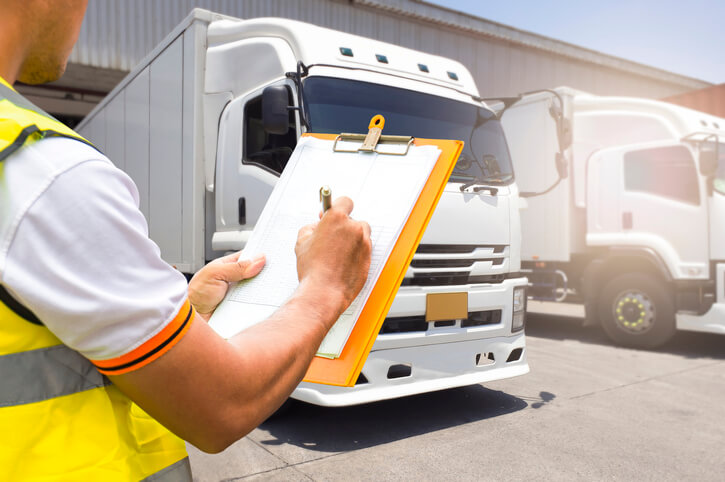 A male dispatcher going through a checklist at a parking lot after completing his automotive training