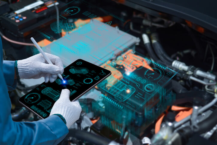 A male auto mechanic diagnosing a hybrid vehicle engine's ECU system after completing his hybrid and electrical mechanic training.