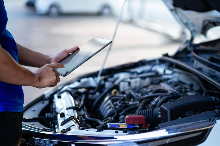 A male auto mechanic accessing the condition of an EV battery after completing automotive school