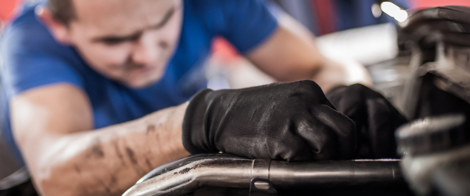 Male auto mechanic checking and fixing the engine of a vehicle