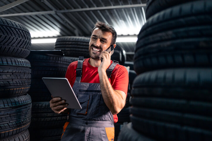 An auto parts training grad on the phone surrounded by tires