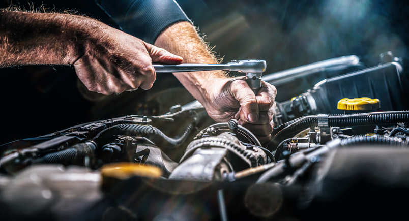 Auto mechanic working on the engine of a vehicle after completing his auto mechanic training