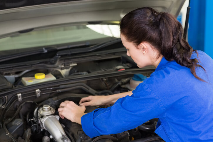 A female auto mechanic monitoring the engine of a vehicle