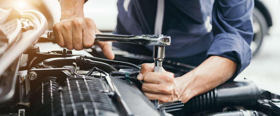 Male auto mechanic working on the engine of a vehicle in a repair shop