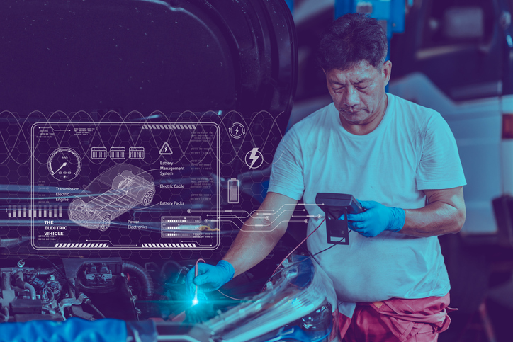 Male mechanic diagnosing the voltage of an EV battery after completing his hybrid technology training