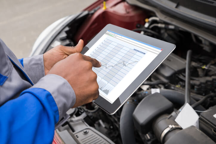 Auto mechanic diagnosing regenerative braking systems with the use of specialized software