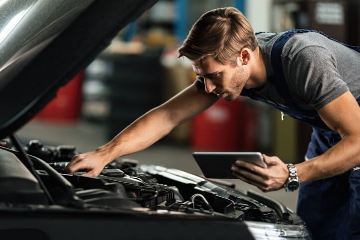 An automotive training grad working with a tab to inspect a vehicle