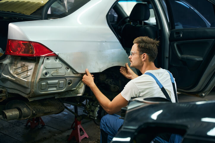 A focused male auto body estimator accessing replacement parts for a damaged vehicle after completing his auto body estimating training