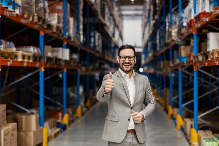 A male dispatcher giving the thumbs-up sign in a warehouse after completing his dispatch training