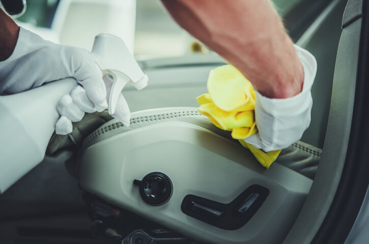 A professional auto detailer using eco-friendly cleaning products during a chemical-free auto detailing session