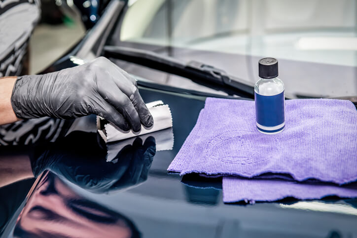 An auto detailing specialist applying iron removal solution on the exterior of a vehicle after completing his auto detailing training