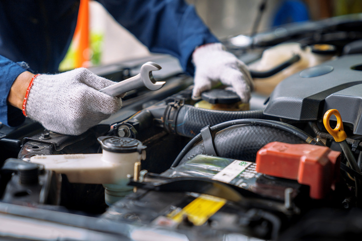 Male auto mechanic repairing a vehicle at a garage after completing his auto mechanic training