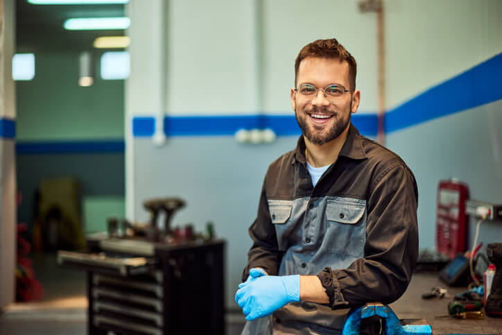 A male auto mechanic trainee studying for an apprenticeship at an auto mechanic school