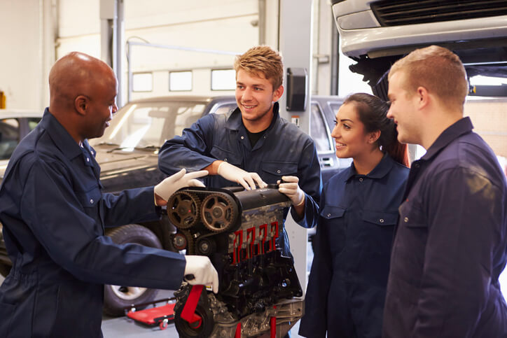 An auto mechanic training students having a discussion with an experienced instructor