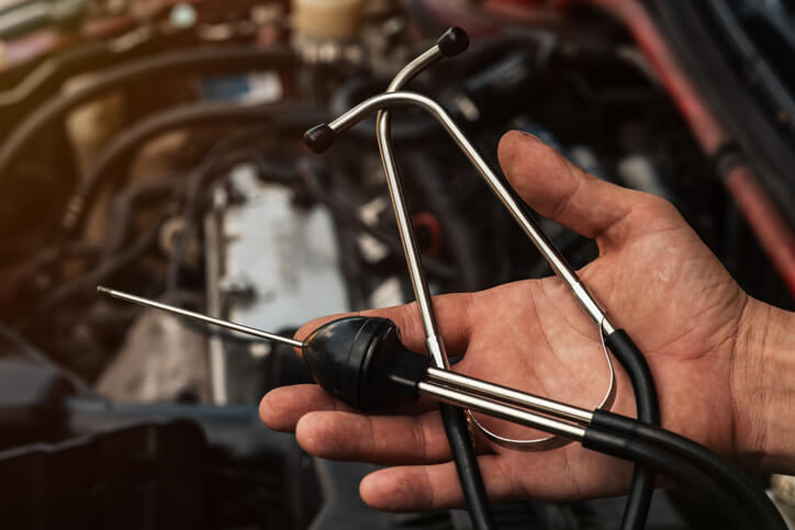 A male auto mechanic holding a stethoscope in his hand after completing automotive school