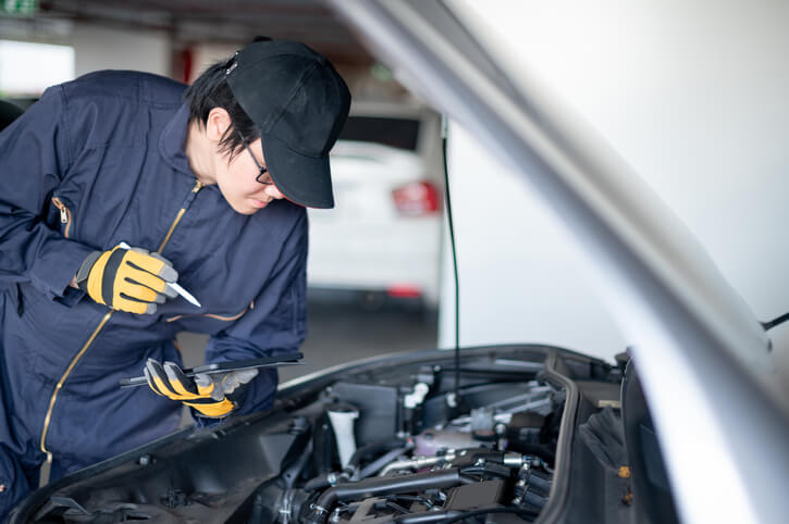 A male hybrid and electric vehicle mechanic working on a vehicle at a repair shop