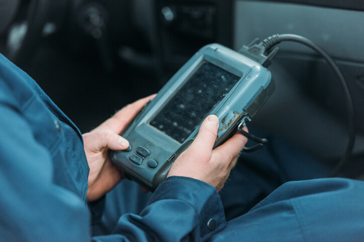 A hybrid and electric vehicle mechanic using a diagnostic tool and reading a trouble code from a hybrid vehicle’s onboard computer