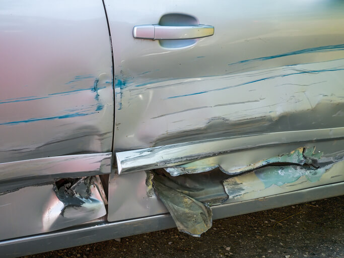 A close-up of a car’s scratched bumper in an automotive school.