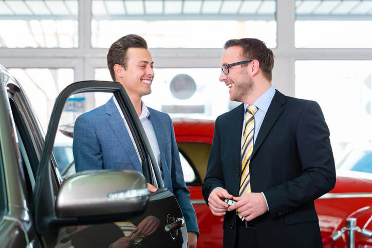 A pair of professionals exchanging business cards at an auto careers networking event.