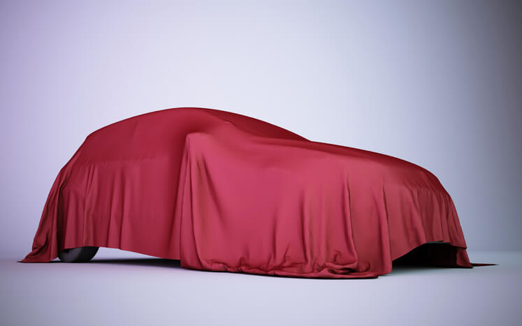 A red sheet draped over a small car as observed by an auto mechanic training grad